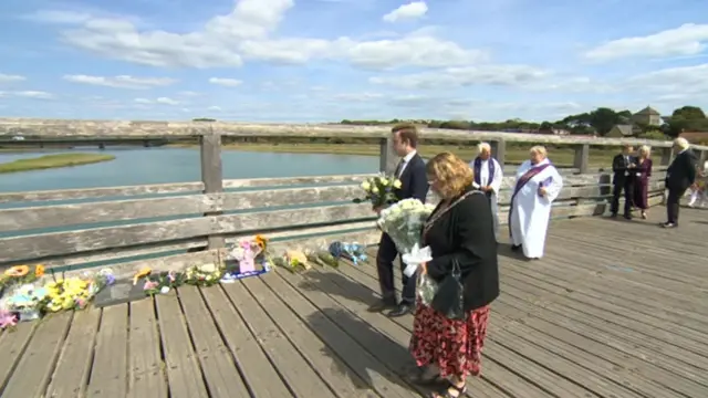 People laying down flowers at the anniversary site in Shoreham.