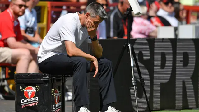 Paolo Pezzolano covers his face while sat on a box