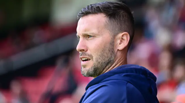 Walsall manager Mat Sadler looking out onto the football pitch with his mouth open.