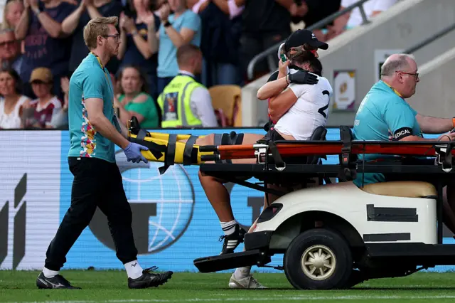 Kaipo Olsen-Baker is stretchered off with her leg strapped up. She's in tears.