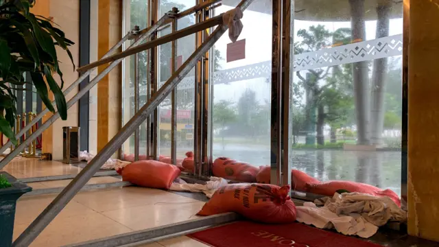 A landscape shot of metal bars propped up against the windows and doors of a hotel. Sandbags have also been lain at the bottom