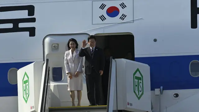 South Korean President Lee Jae Myung (right) and his wife wave just before entering the presidential plane.
