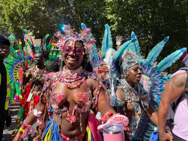 A group of women smile at the camera as they dance as part of the parade