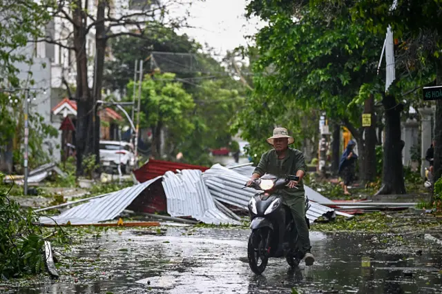 A man rides a scooter past debris on a street after Super Typhoon Yagi hit Hai Phong on September 7, 2024. Super Typhoon Yagi uprooted thousands of trees and swept ships and boats out to sea