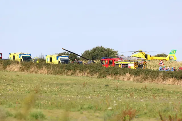 yellow Hampshire and Isle of Wight Air Ambulance stationed in the field as emergency crews work at the scene
