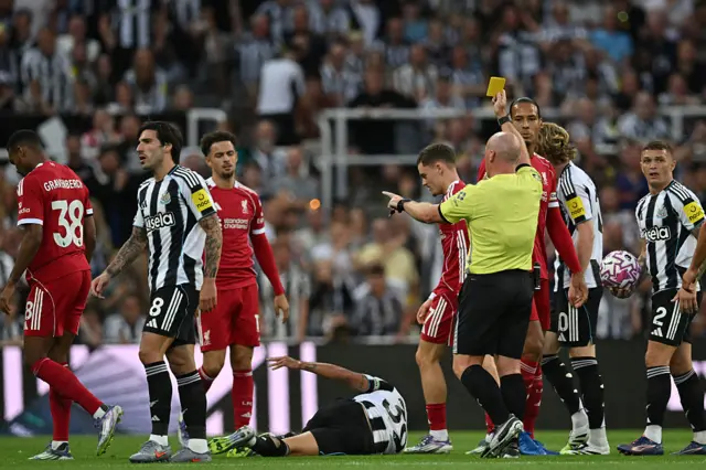 English referee Simon Hooper shows a yellow card to Liverpool's Dutch midfielder #38 Ryan Gravenberch