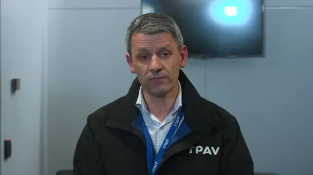 Headshot of Wayne Gatt who stands in front of a blank TV screen