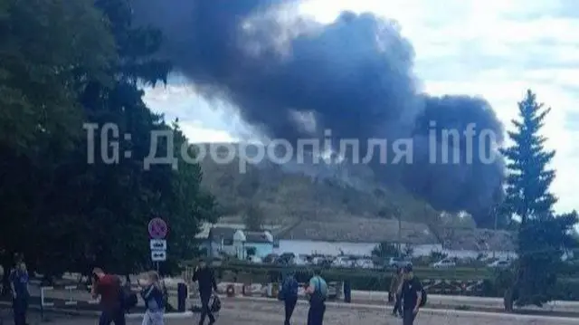 Smoking rising from a mine behind a set of buildings