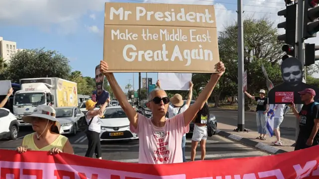 Protesters gather with signs during a demonstration organised by the families of the Israeli hostages taken captive in the Gaza Strip since the October 2023. A person holds up a sign that reads: Mr President, Make the Middle East Great Again