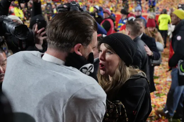 A woman holds a mans face as they celebrate at the end of a football game