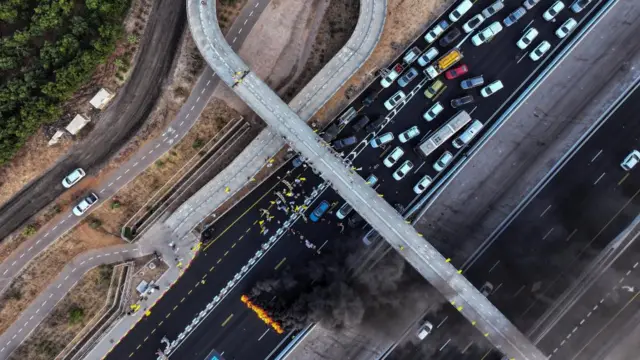 An aerial view of traffic backed up on a road behind a blazing fire