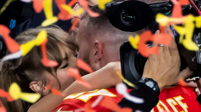 Yellow and white confetti obscures a blond woman hugging a man