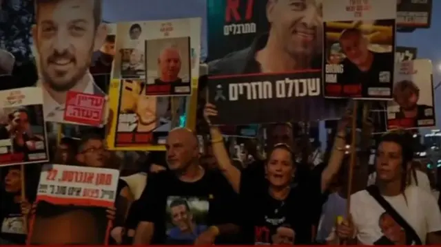People hold up placards of the Israeli hostages as they take part in a rally