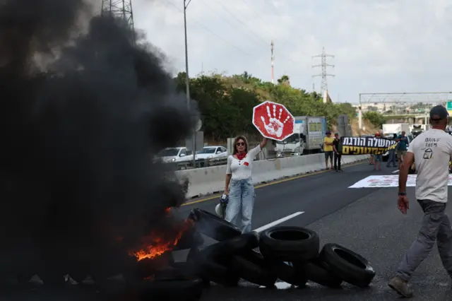 Protesters next to burning tires on the main road at Petah Tikva