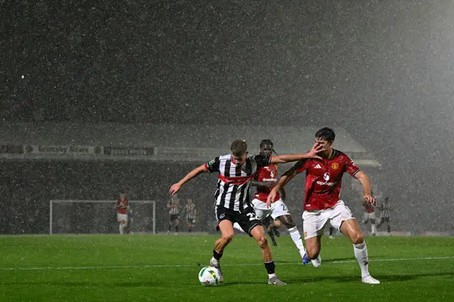 Cameron Gardner of Grimsby Town is challenged by Harry Maguire of Manchester United during the Carabao Cup Second Round match between Grimsby Town and Manchester United at Blundell Park on August 27, 2025 in Grimsby, England.