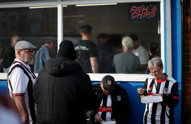 Fans eat fish and chips outside the ground