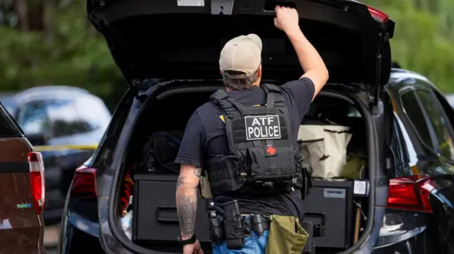 An officer with the ATF opens his trunk while setting up outside the shooting at Annunciation Church