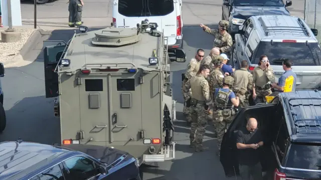 FBI officers in tactical gear assembling next to a nearby auto parts store