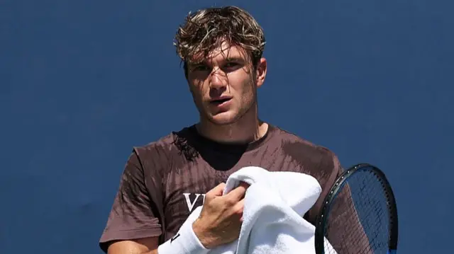 Jack Draper walks back to his chair with his towel during a practice session