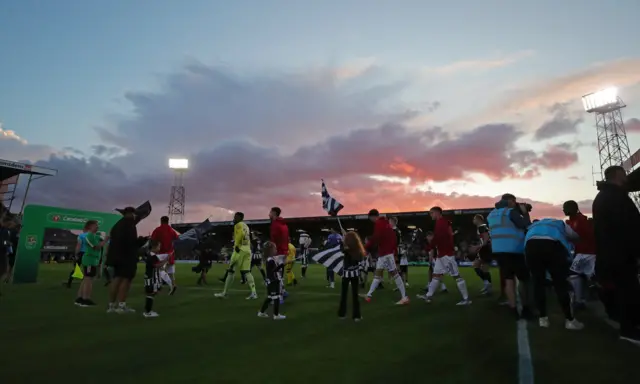 Manchester United and Grimsby Town players head out onto the pitch.