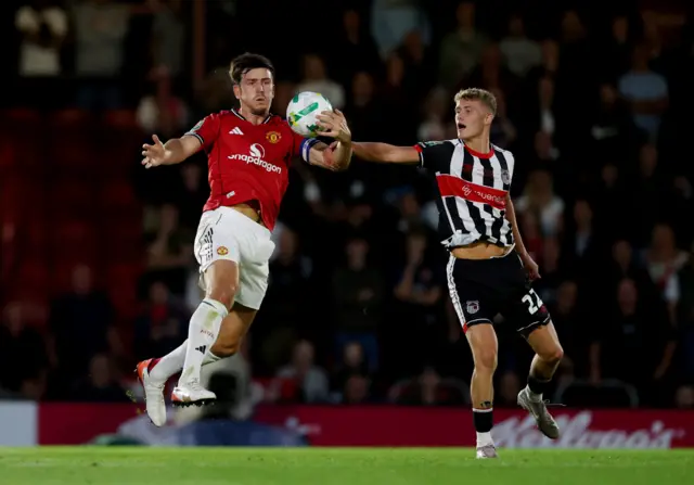 Manchester United's Harry Maguire in action with Grimsby Town's Cameron Gardner