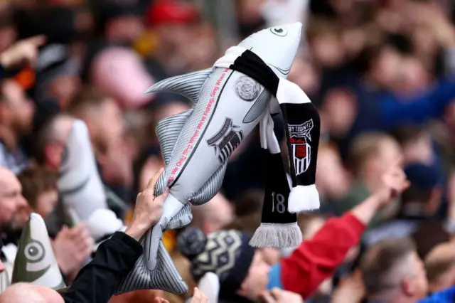 Grimsby town mascot Harry Haddock being waved by a fan in the crowd