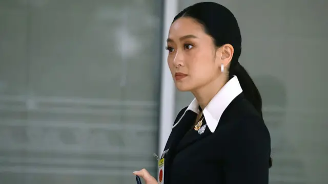 Side view of Paetongtarn with a neat ponytail, wearing a black blazer
