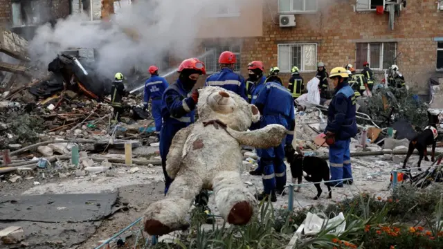 A rescuer holds a soft toy at the site of an apartment building which was hit by Russian missile and drone strikes