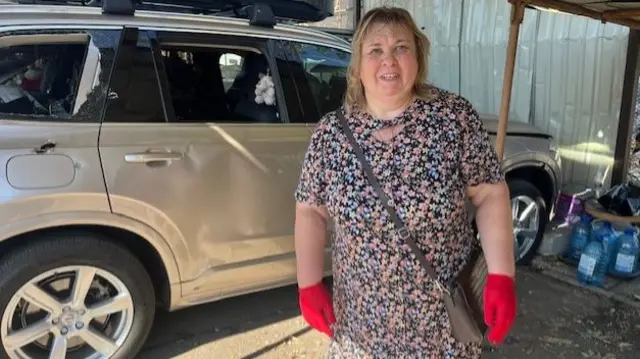 A Ukrainian woman standing next to a car