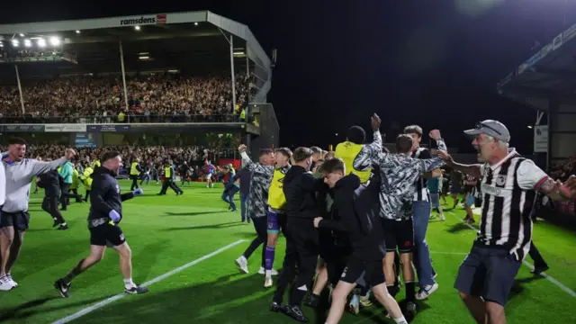 Grimsby fans on the field celebrating their team's EFL Cup win over Manchester United