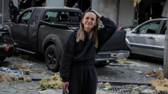 A woman cries as she stands at the site of an apartment building hit during Russian drone and missile strikes