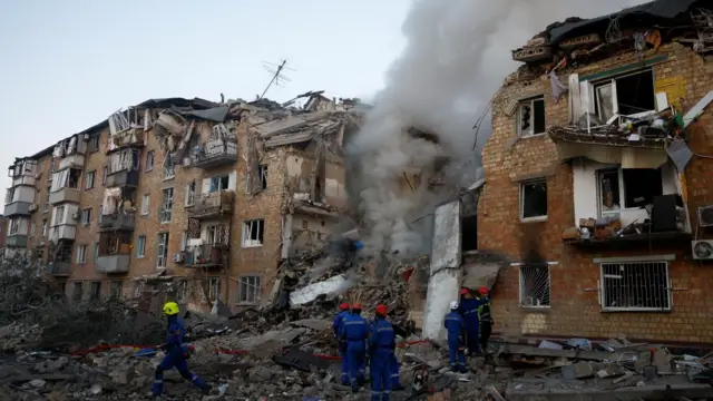 Rescuers work at the site of a building which was hit by Russian missile and drone strikes
