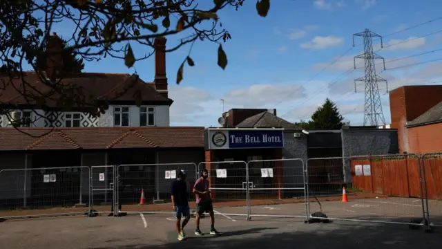 Two men walk past the entrance of The Bell Hotel in Epping.