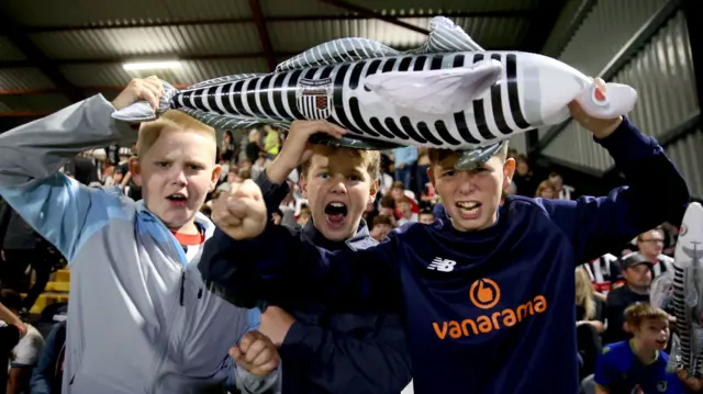 Grimsby fans on the field celebrating their team's EFL Cup win over Manchester United