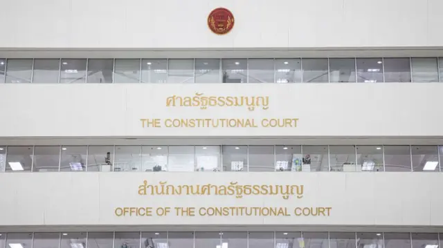 "The Constitutional Court" in bright yellow letters along the wall of a building, with Thai letters above.