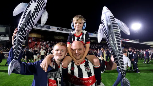 Grimsby fans on the field celebrating their team's EFL Cup win over Manchester United