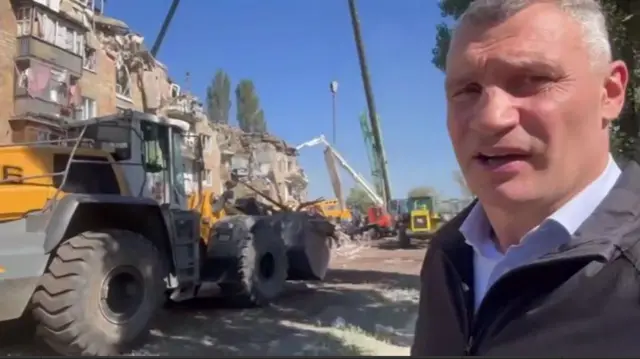 Vitaly Klitschko standing next to a collapsed building