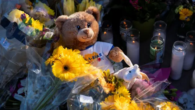 Flowers and stuffed animals sit at an intersection near the Annunciation Church