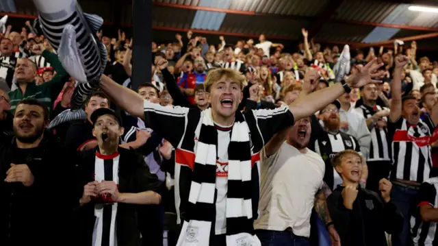 Grimsby fans on the field celebrating their team's EFL Cup win over Manchester United