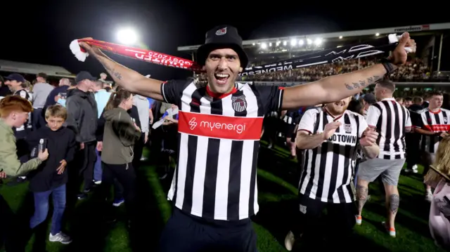 Grimsby fans on the field celebrating their team's EFL Cup win over Manchester United