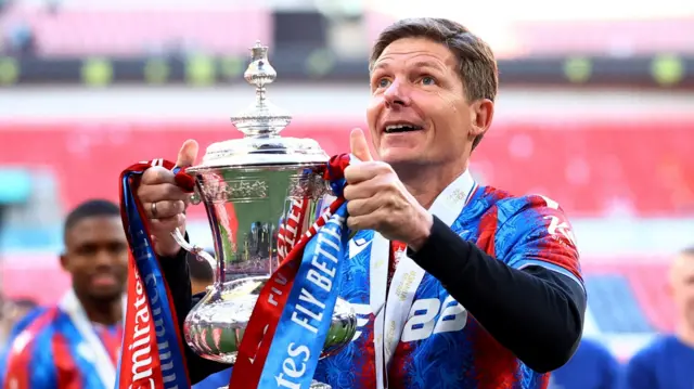 Crystal Palace manager Oliver Glasner smiling while holding the FA Cup