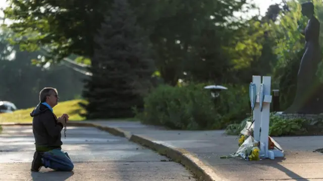 Mourner Tim Barr prays outside the Annunciation Church