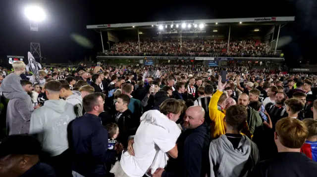 Grimsby fans on the field celebrating their team's EFL Cup win over Manchester United