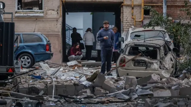 People gather at the site of buildings hit by Russian missile and drone strikes