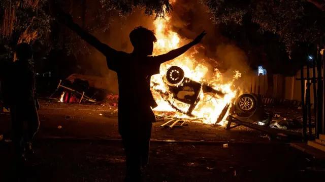 A man walks past a burning car after it was set ablaze during a protest at Yogyakarta Police headquarters