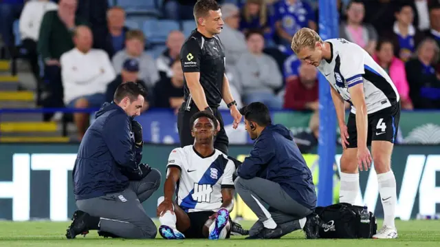 Demarai Gray looks in pain as he receives treatment on a shoulder injury