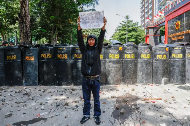 Man holding banner in front of police in Indonesia