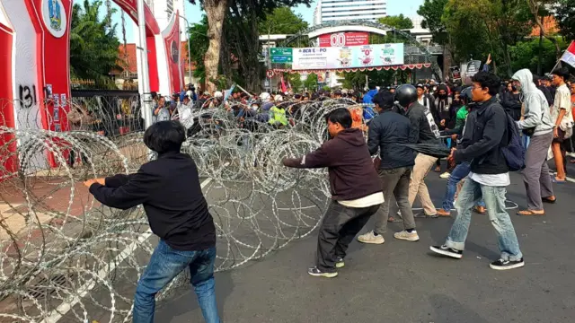 Protestors try to dismantle barbed wire in the city of Surabaya