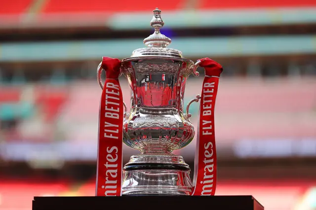The FA Cup trophy on a podium at Wembley Stadium