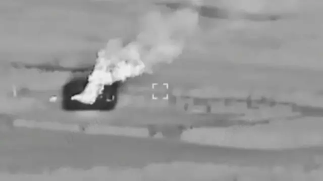 A screenshot of night-vision footage of an explosion in the distance
